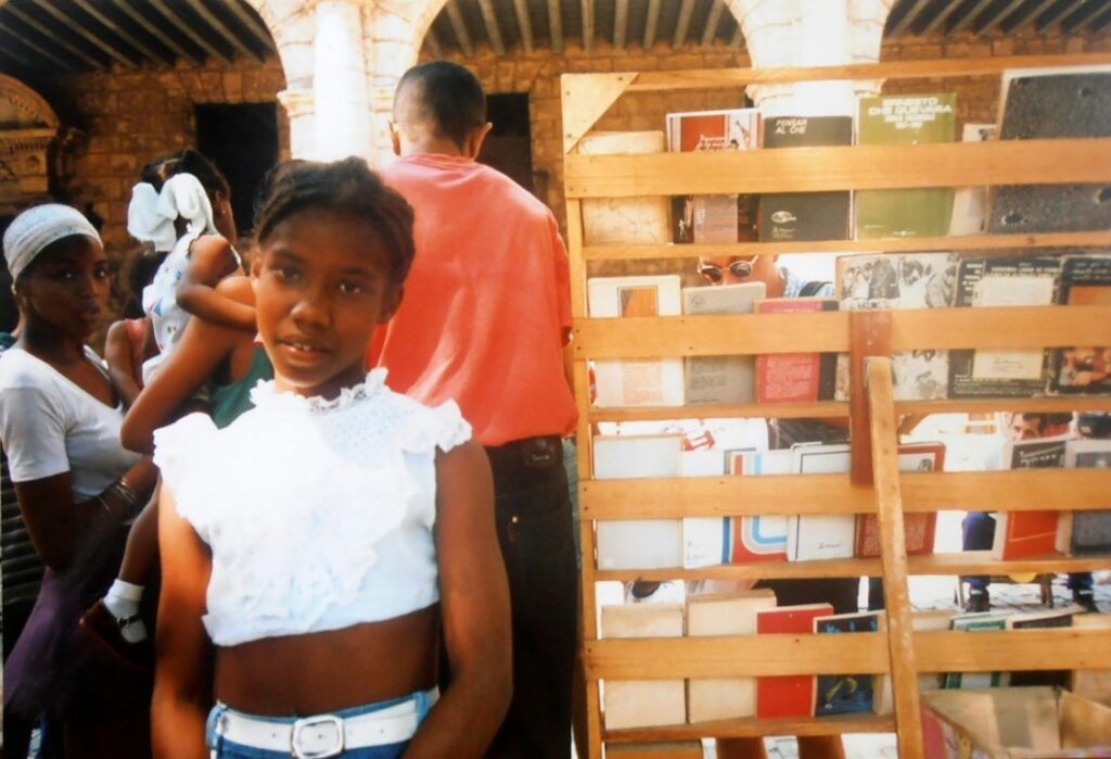 Una bambina posa vicino ad una bancarella di libri a l'Habana, Cuba